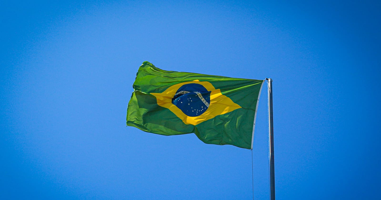 Bandeira do Brasil no mastro contra o céu azul